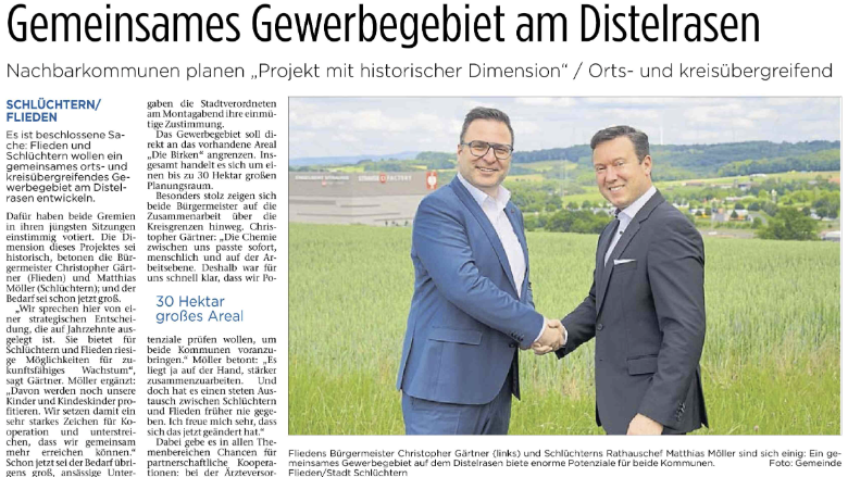 Grundsatzbeschluss für die gemeinsame Gewerbeentwicklung von Flieden und Schlüchtern Die Bürgermeister Gärtner und Möller reichen sich die Hand auf einer Wiese am Diselrasen