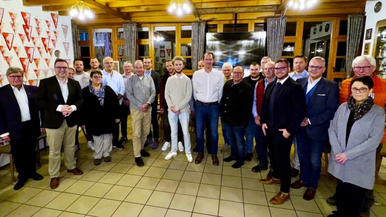Kandidatinnen und Kandidaten der CDU Flieden für die Kommunalwahl 2026 Gruppenfoto von mehreren Personen in einem Versammlungsraum mit Holzdecke und Wimpeln an der Wand. Alle stehen zusammen und lächeln in die Kamera.